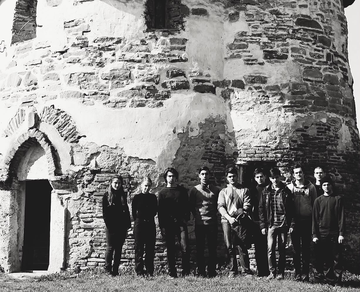 Archival photograph, 2014, Romania; group of participants standing before a weathered masonry building during an educational residential plein-air art programme.