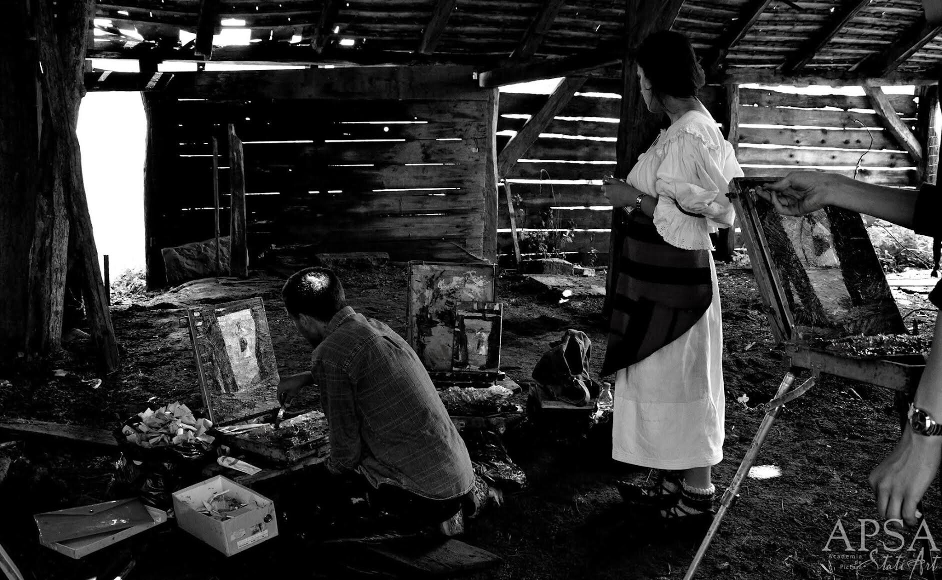 Archival photograph, 2016, Sibiu, Romania; participants working with canvases and painting materials inside a rustic wooden structure during a plein-air programme.